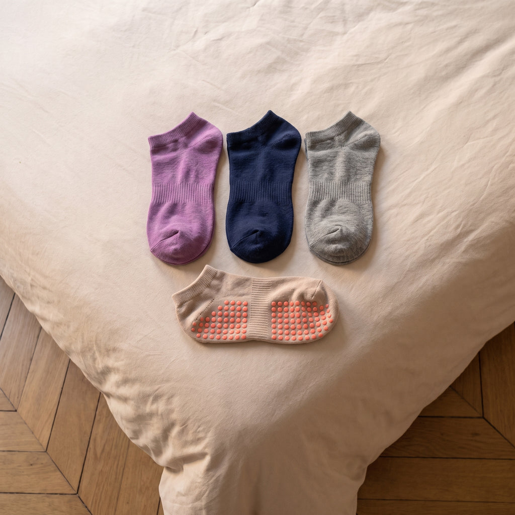 Trois paires de chaussettes antiderapantes pliees sur le lit et une semelle a picots