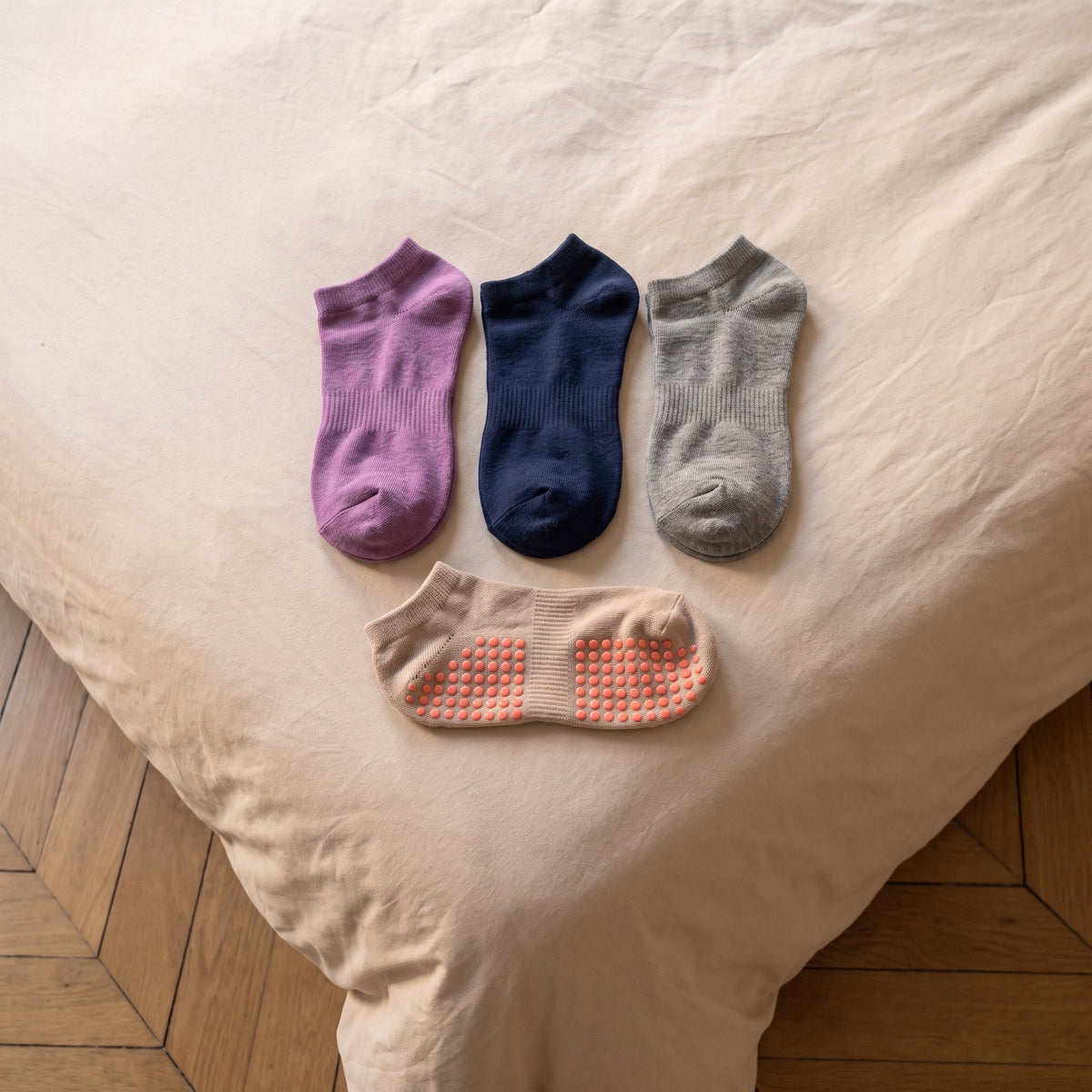 Trois paires de chaussettes antiderapantes pliees sur le lit et une semelle a picots
