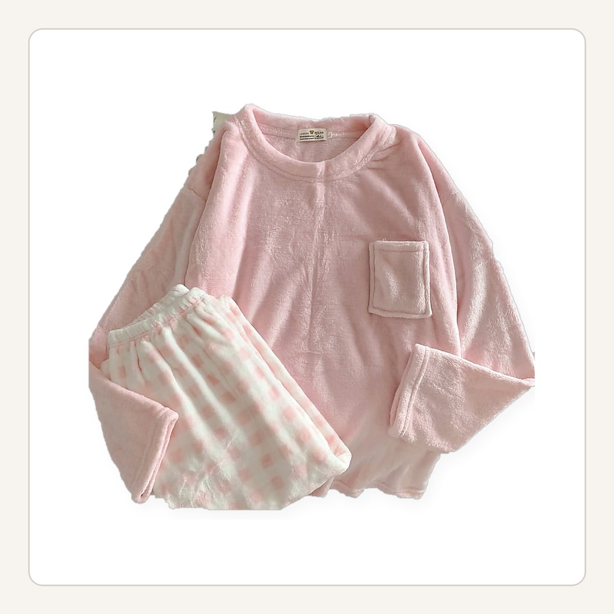 Ensemble de pyjama en flanelle rose posé à plat, haut uni à poche et bas à carreaux.