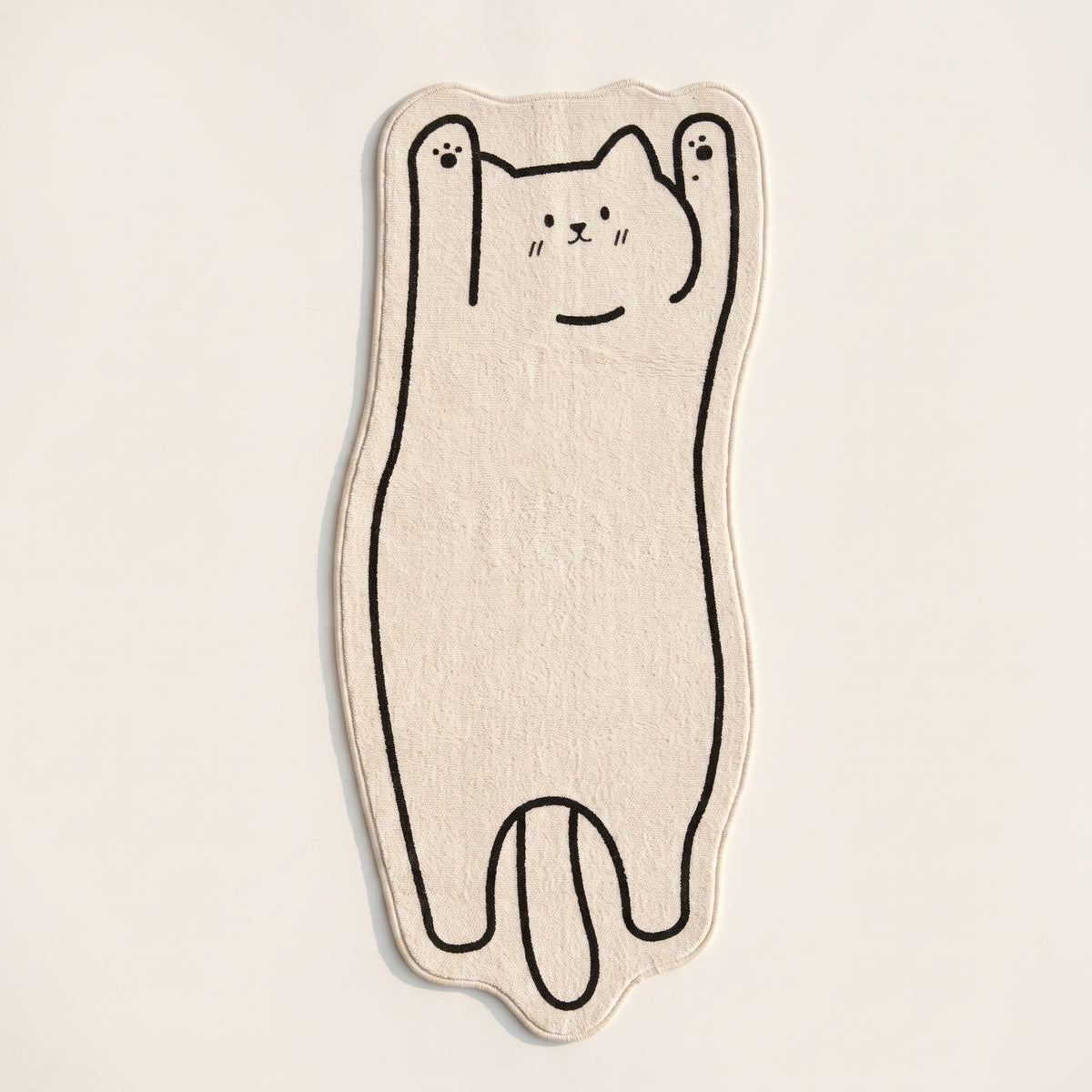 Packshot du tapis chat cartoon vu du dessus sur fond blanc cassé
