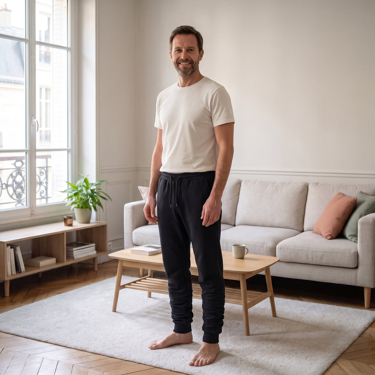 Homme portant le pantalon de jogging noir dans un salon lumineux