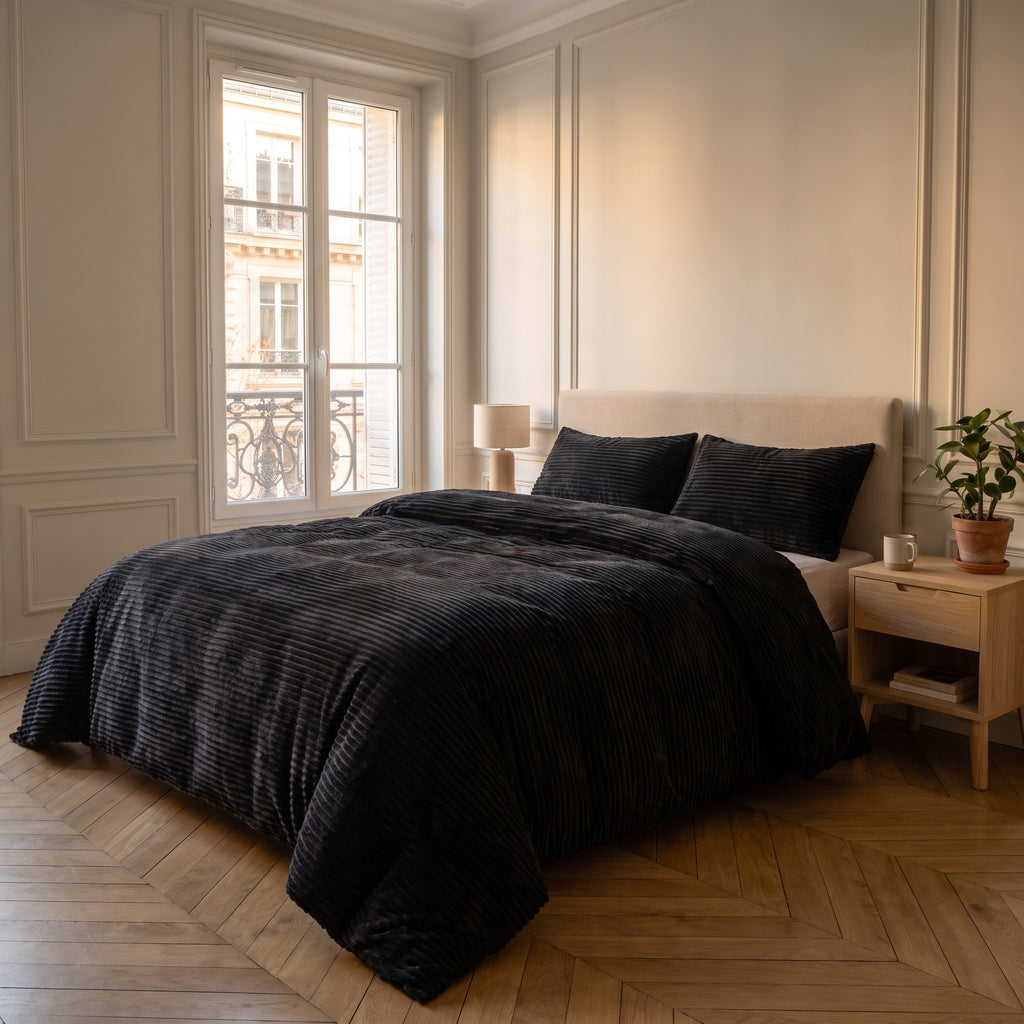 Parure de lit noir uni installée sur un lit dans une chambre lumineuse