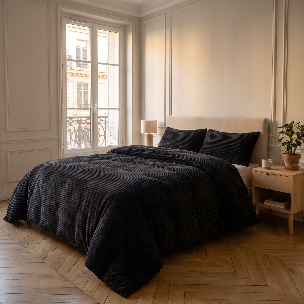 Parure de lit noir uni installée sur un lit dans une chambre lumineuse