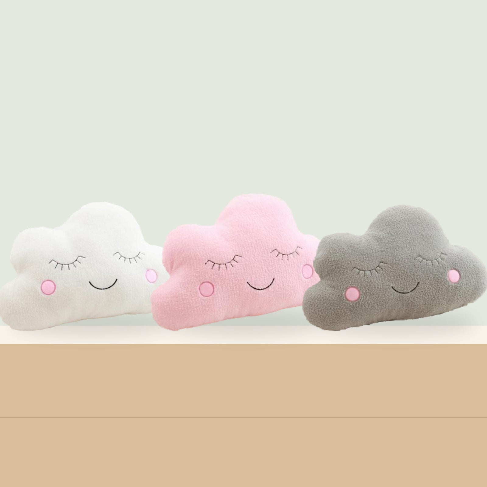 Peluches nuage blanche, rose et grise séparées dans un décor pastel au mur vert sauge Image