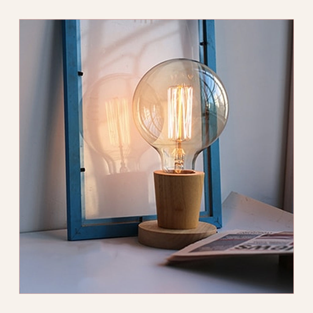 Lampe de table rétro modèle 2 à base évasée, allumée devant une fenêtre
