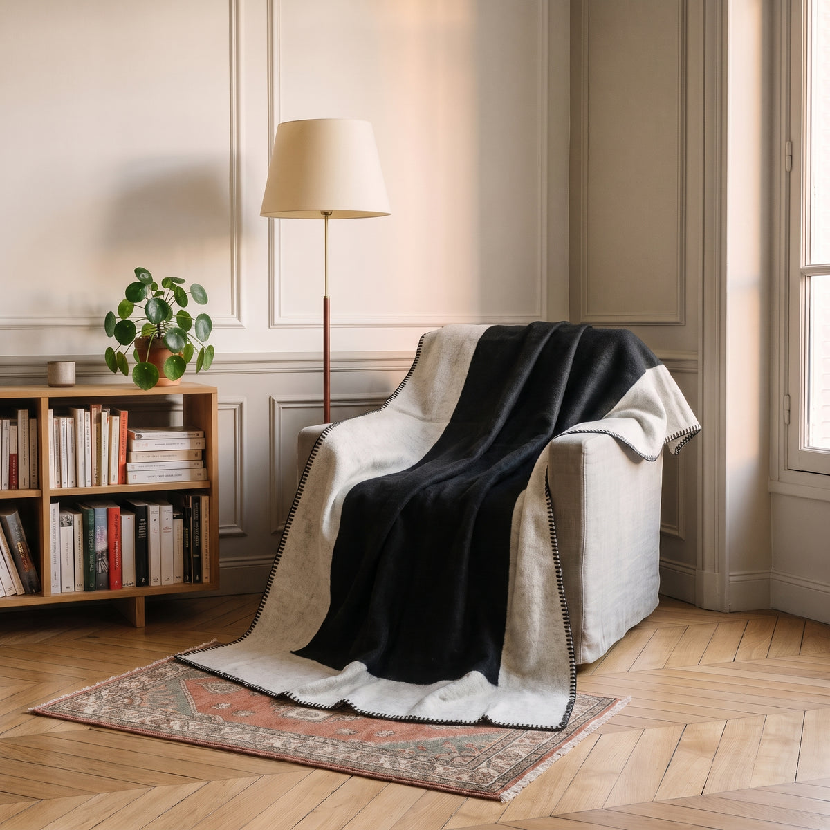Plaid bicolore noir et écru déployé sur un fauteuil
