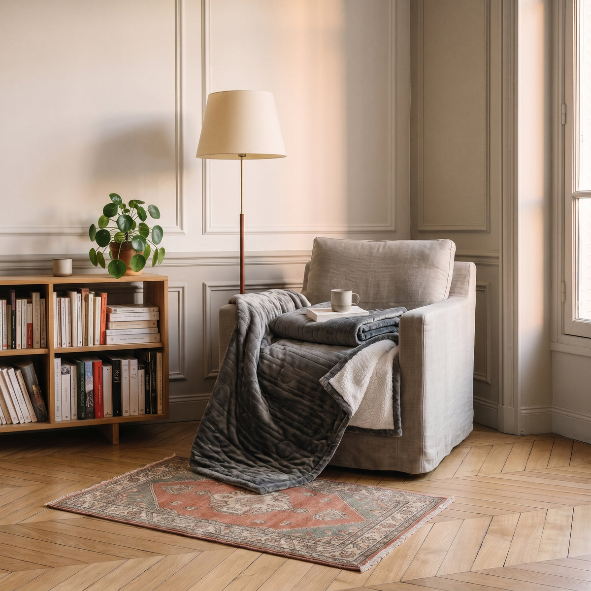 Plaid chauffant gris anthracite 80 x 150 cm replié sur le fauteuil du coin lecture