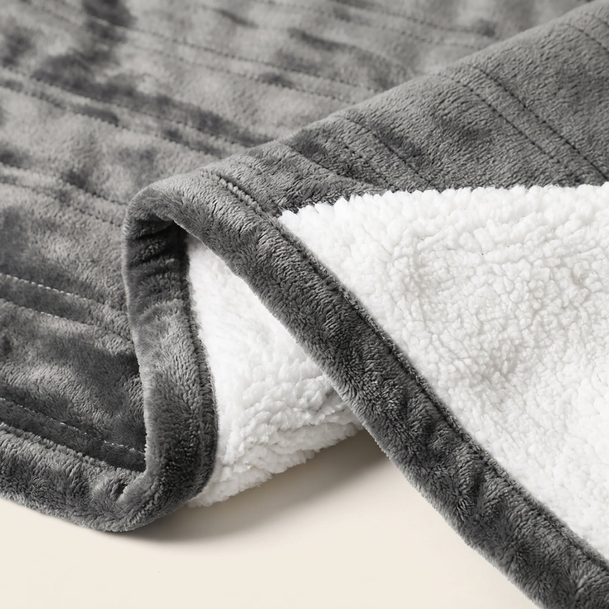 Gros plan sur la face gris anthracite et l'envers blanc du plaid chauffant