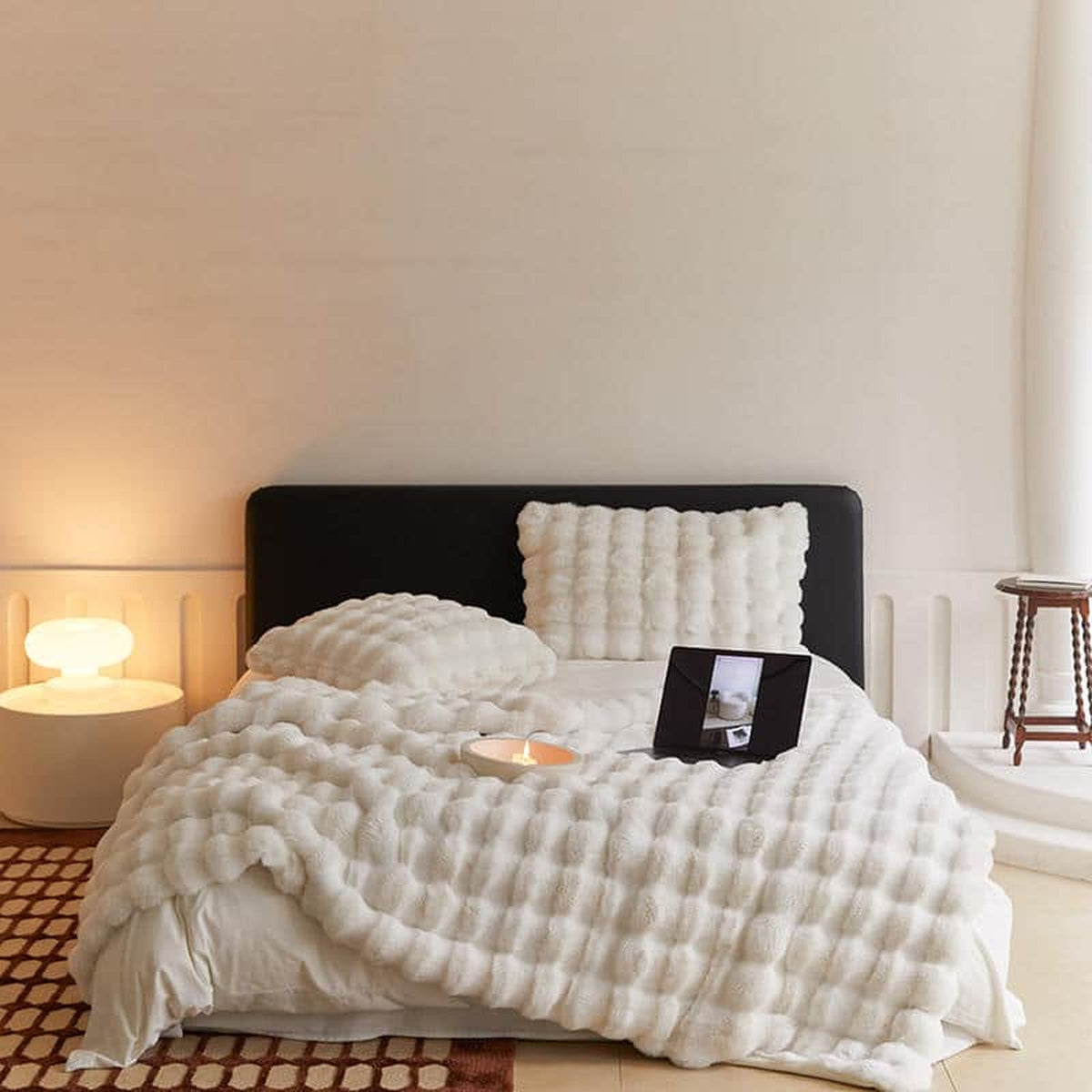 Plaid blanc imitation fourrure déployé sur un lit double, avec sa retombée et ses rangées en relief visibles