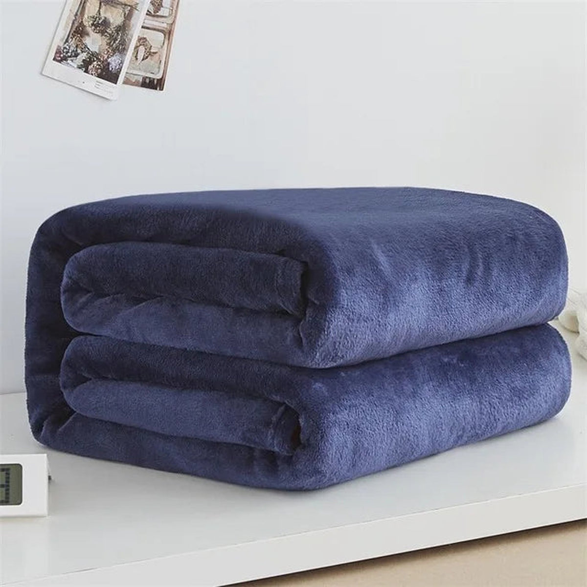 Plaid polaire léger coloris bleu foncé plié sur fond clair