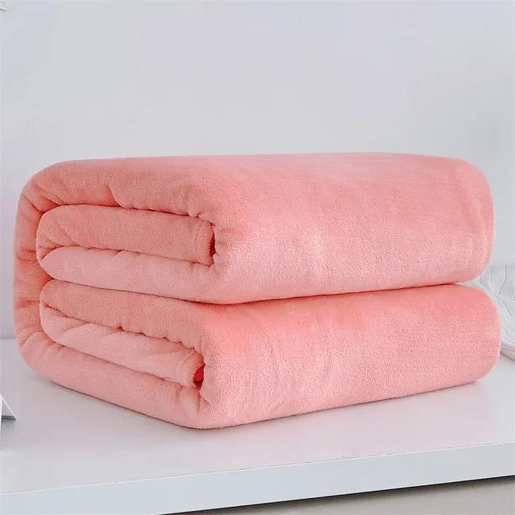 Plaid polaire léger coloris rose corail plié sur fond clair