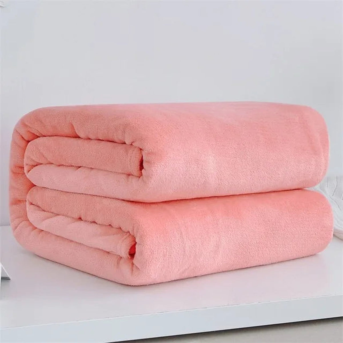 Plaid polaire léger coloris rose corail plié sur fond clair