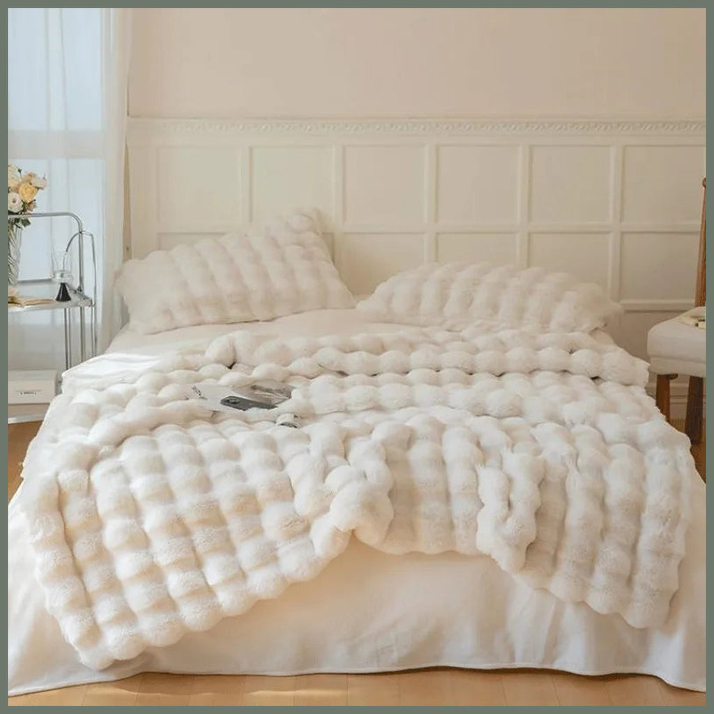 Plaid beige imitation fourrure déployé sur un lit double pour montrer son relief et son échelle