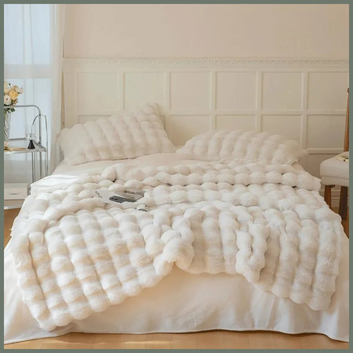 Plaid beige imitation fourrure déployé sur un lit double pour montrer son relief et son échelle