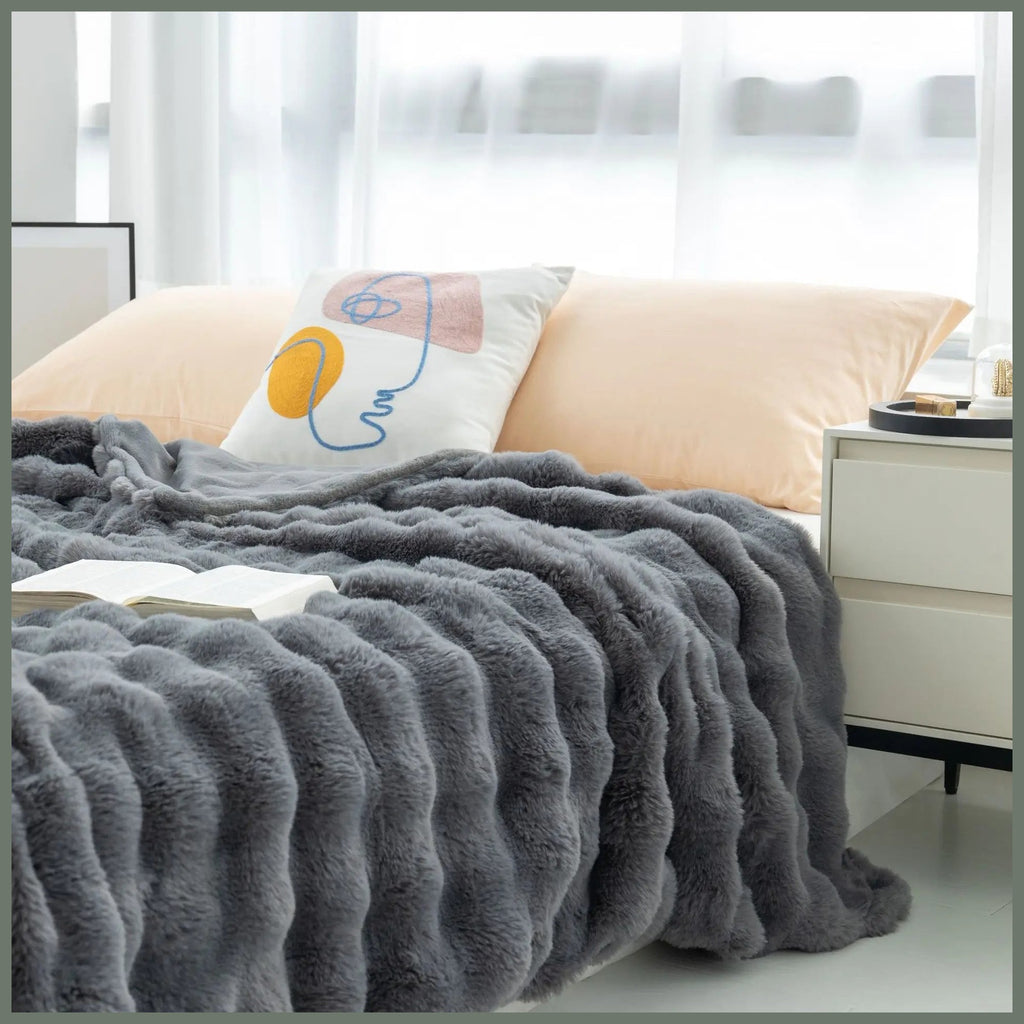 Plaid gris imitation fourrure déployé sur un lit, avec ses rangées en relief visibles