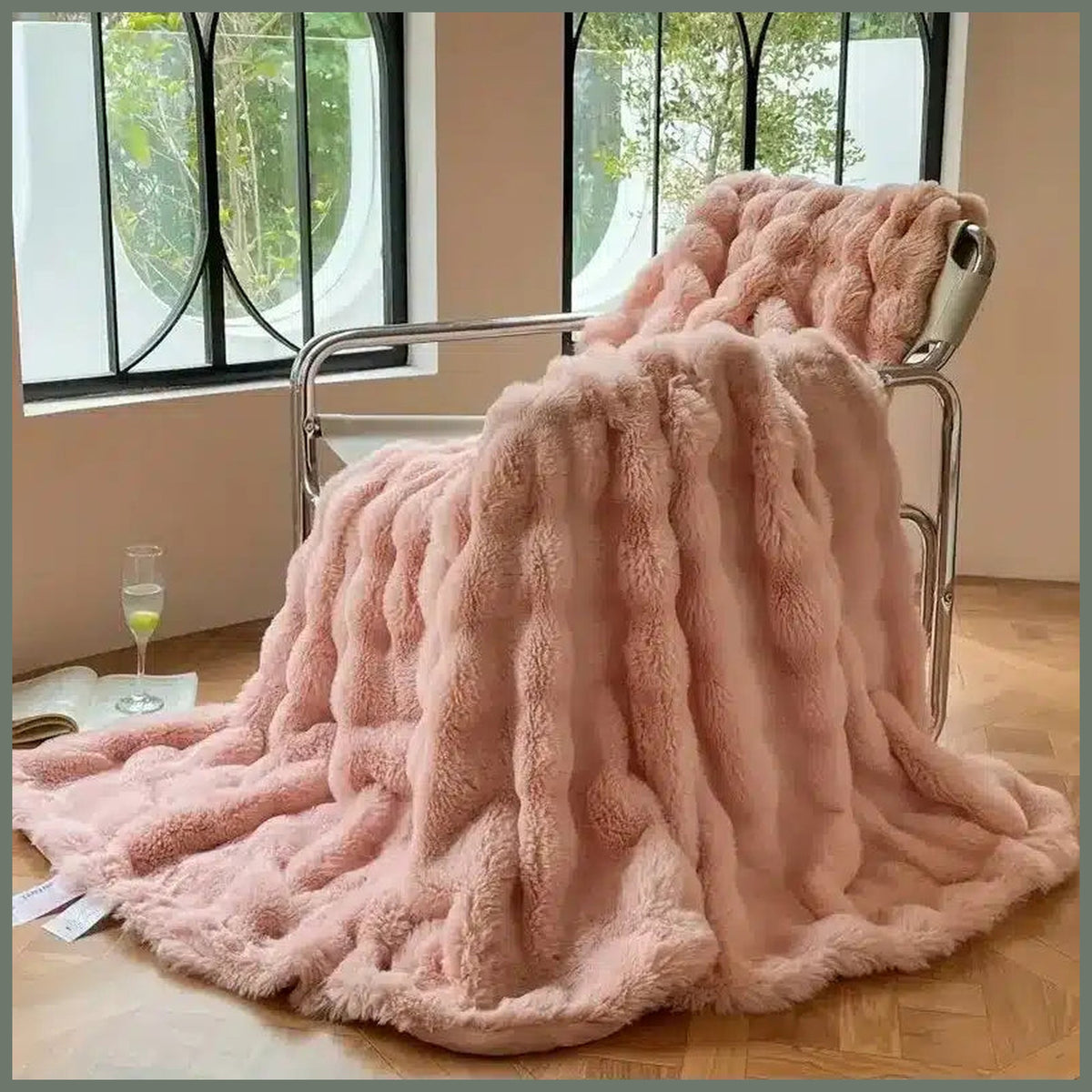 Plaid rose imitation fourrure posé sur un fauteuil, avec sa retombée jusqu’au parquet