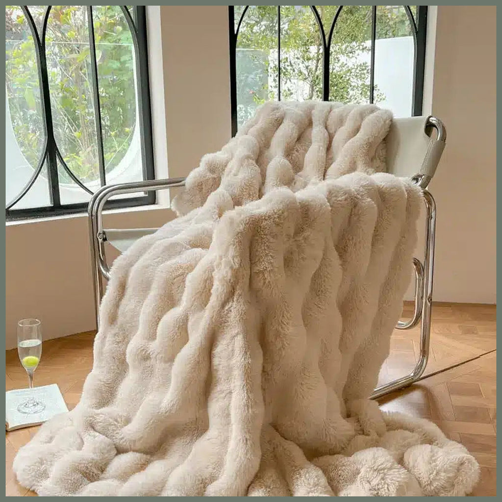 Plaid taupe clair imitation fourrure posé sur un fauteuil, avec ses rangées en relief visibles