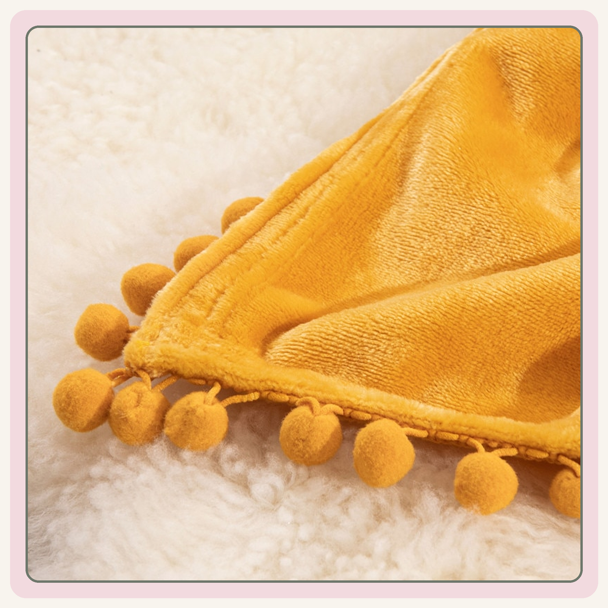 Détail de la bordure et des pompons ronds du plaid jaune