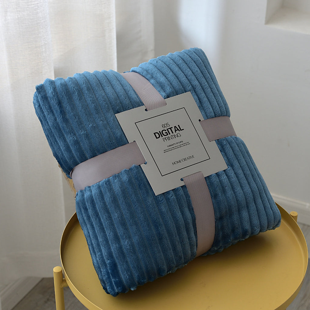 Plaid polaire bleu chaud plié, ses côtes en relief et son emballage visibles
