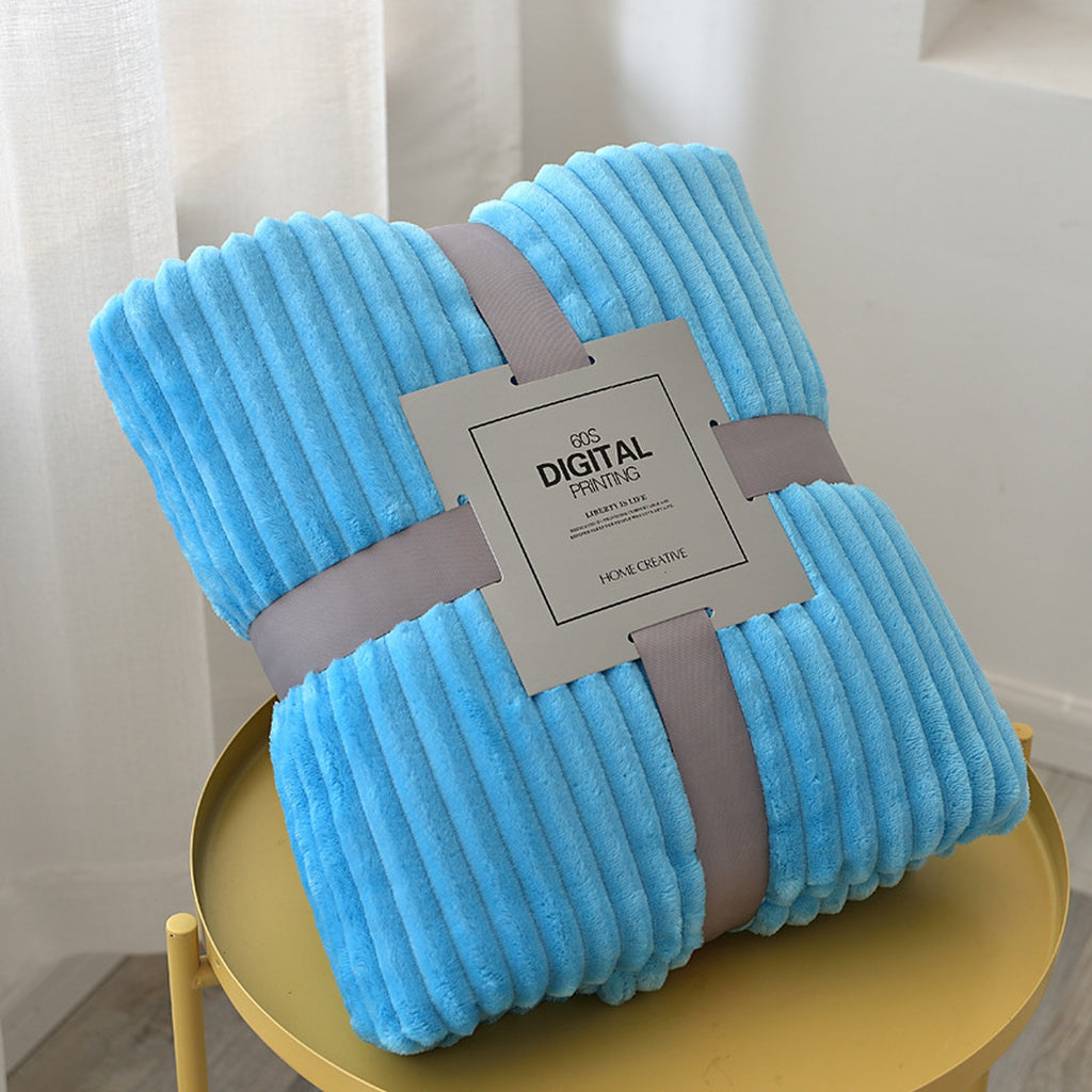 Plaid polaire bleu turquoise plié, ses côtes en relief et son emballage visibles