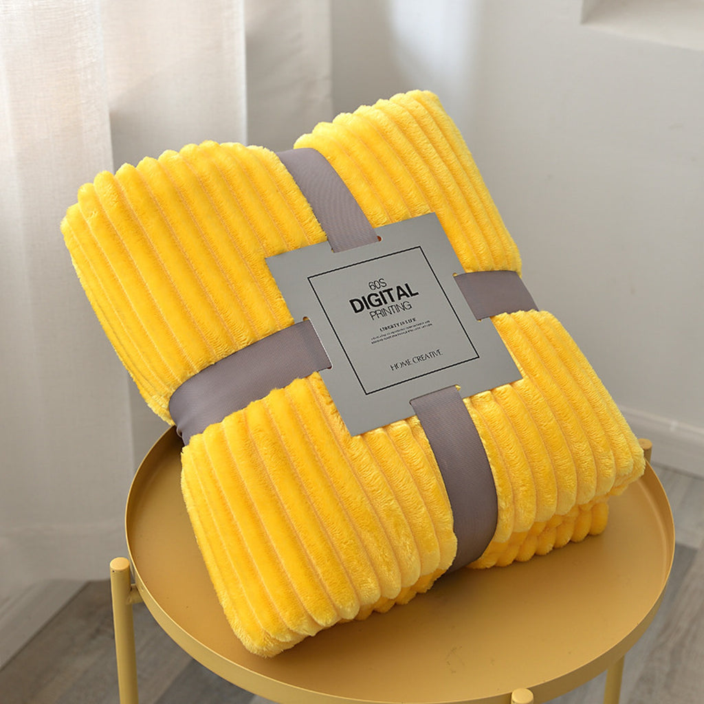 Plaid polaire jaune plié, ses côtes en relief et son emballage visibles