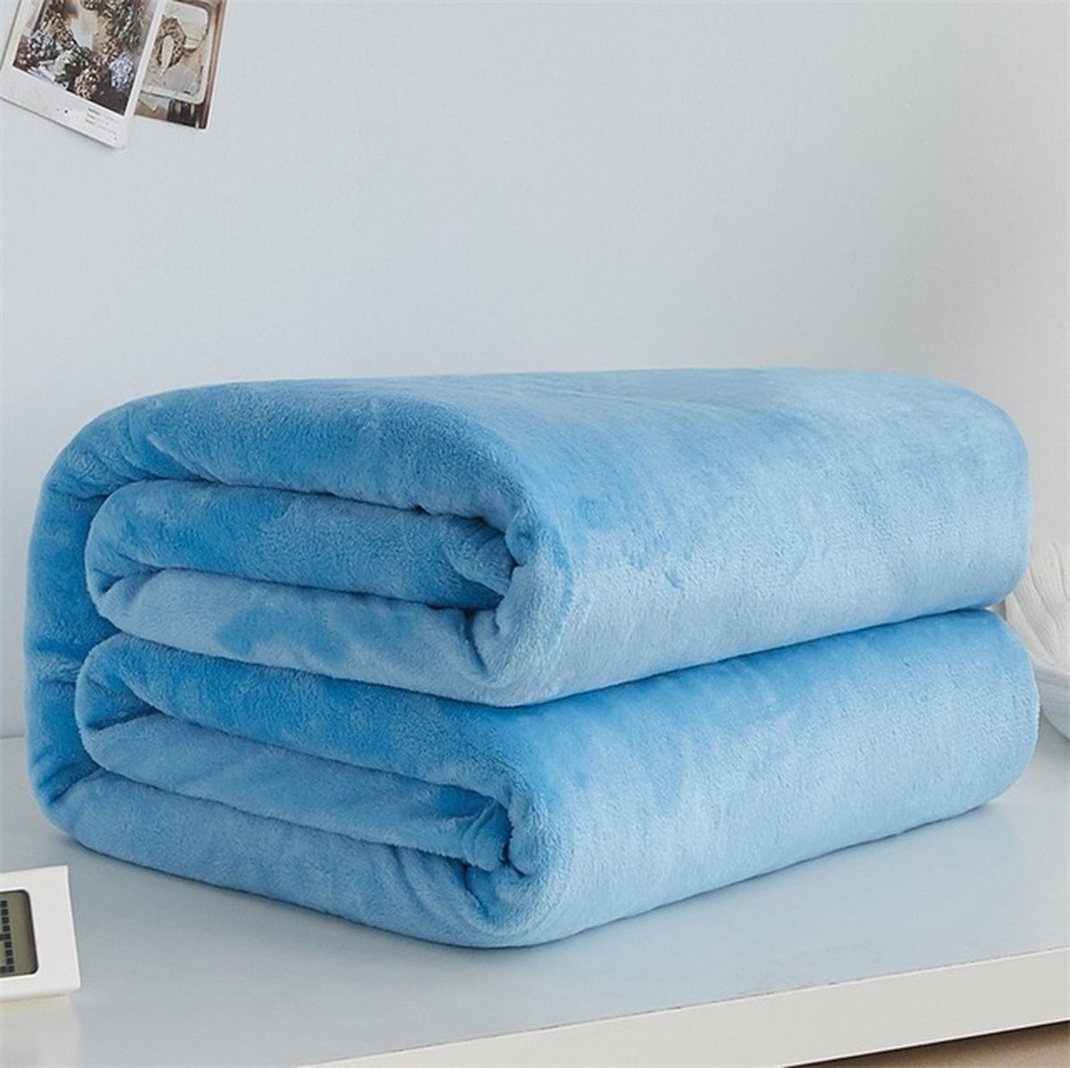 Plaid polaire léger en flanelle coloris bleu clair, plié sur fond clair