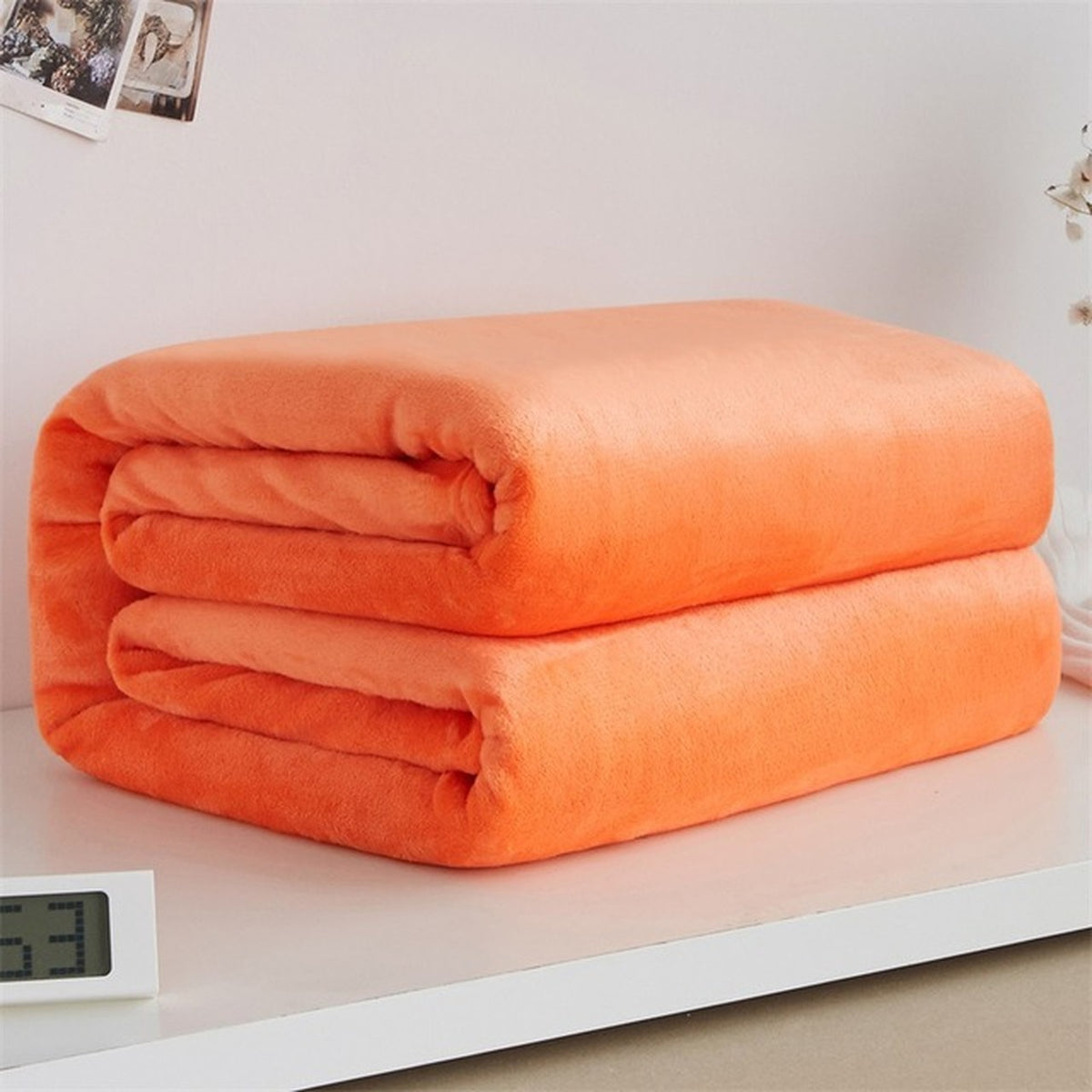 Plaid polaire léger en flanelle coloris orange, plié sur fond clair