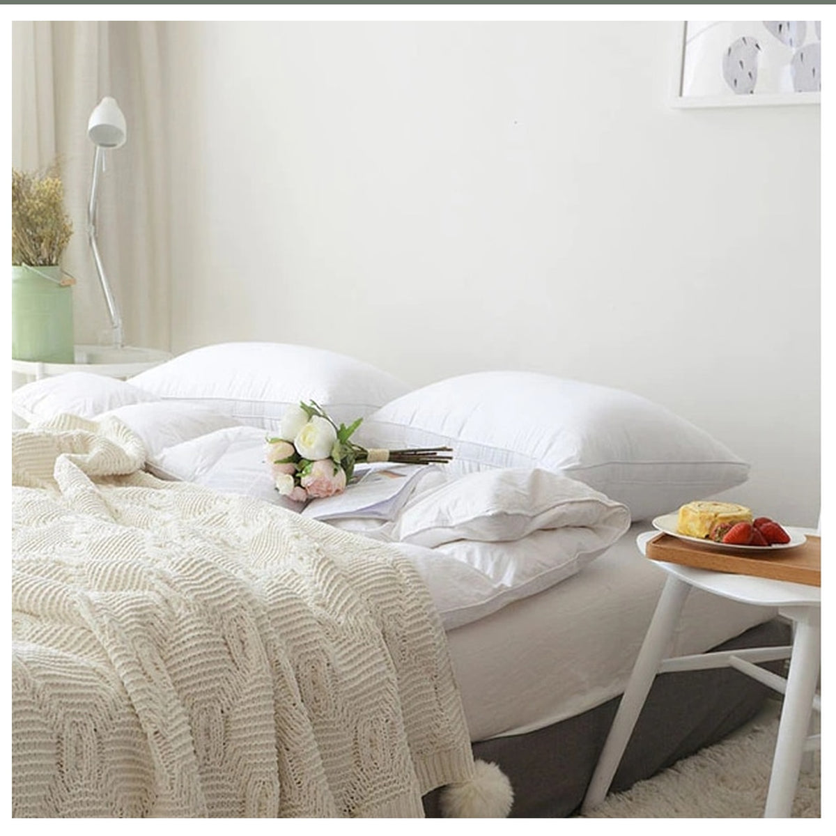 Plaid tricoté beige à pompons montré sur le lit pour donner son échelle