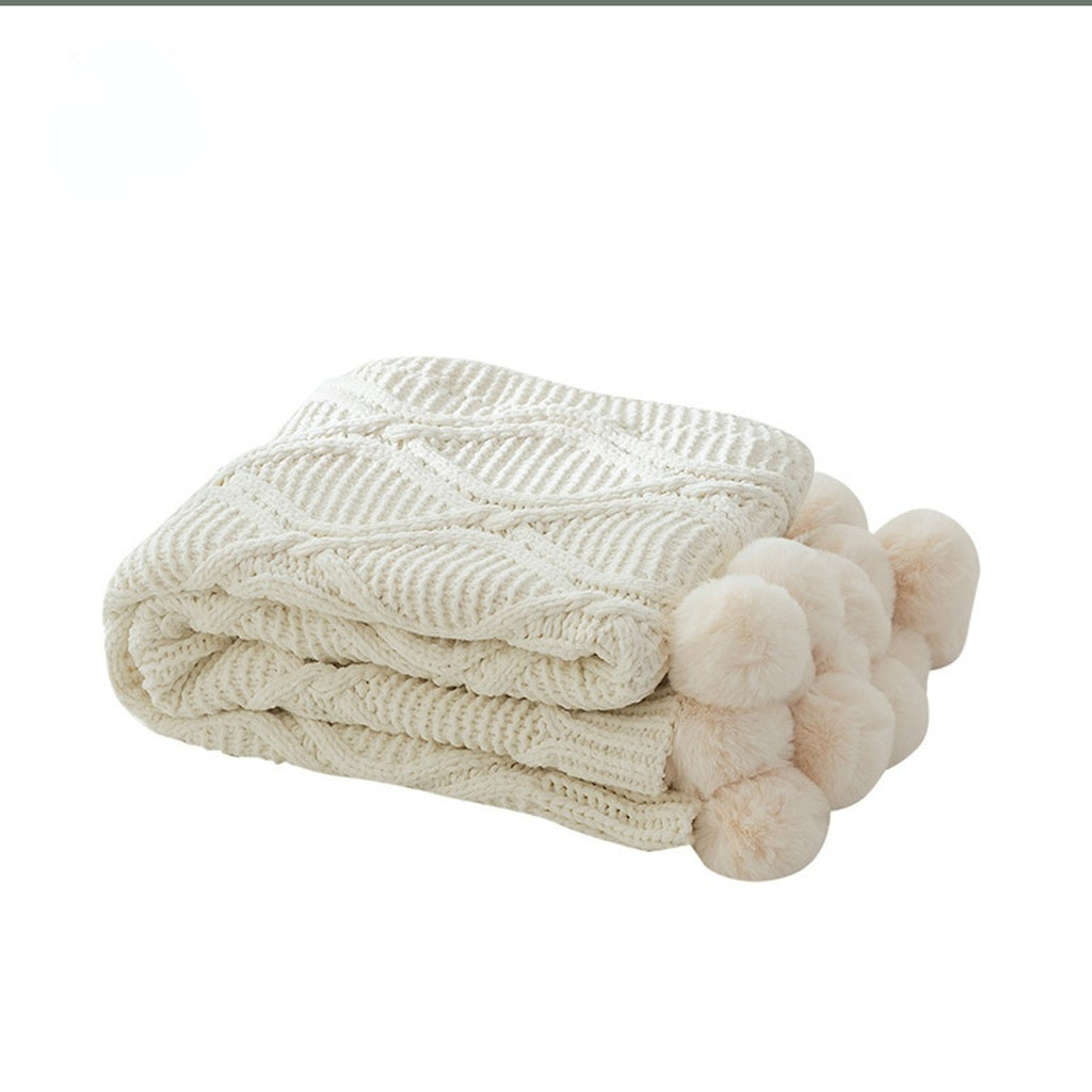 Plaid tricoté beige plié avec ses gros pompons