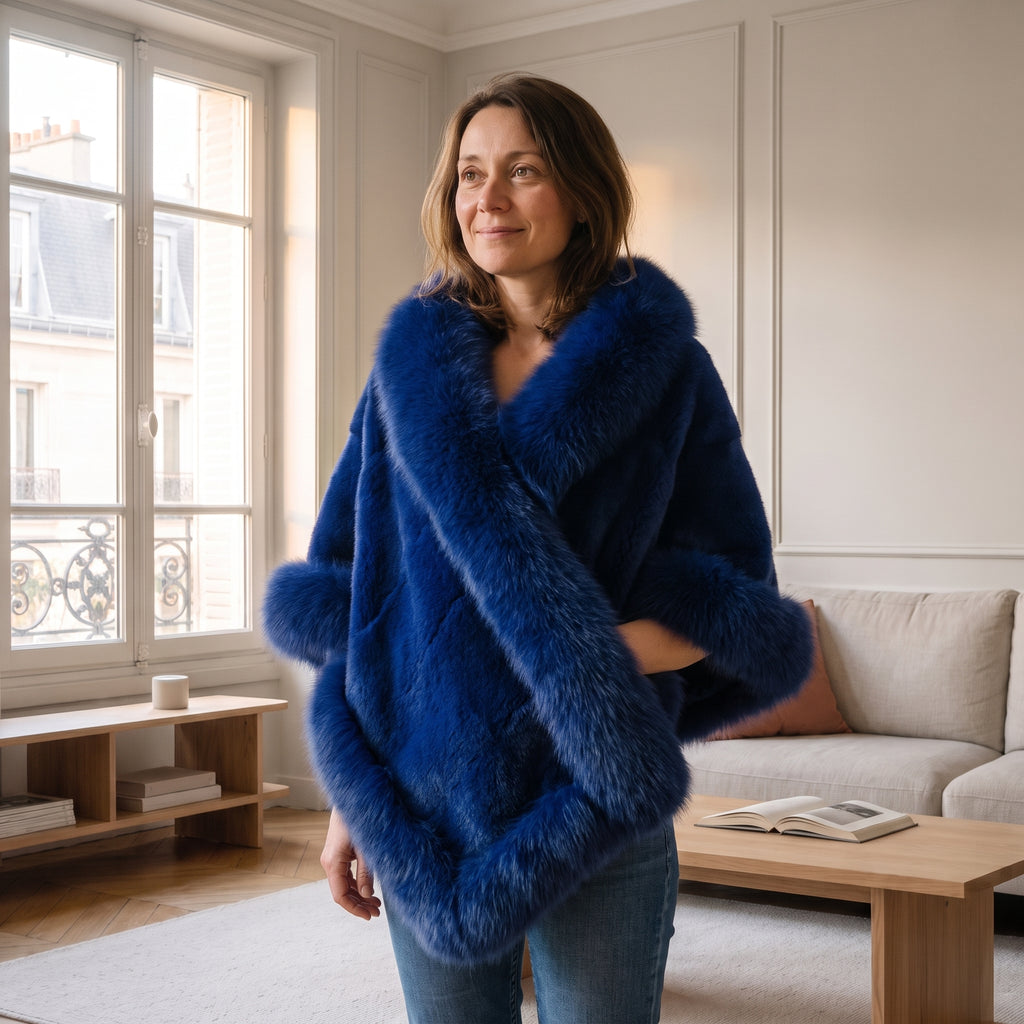 Femme châtain portant le poncho bleu croisé devant, debout dans un salon lumineux