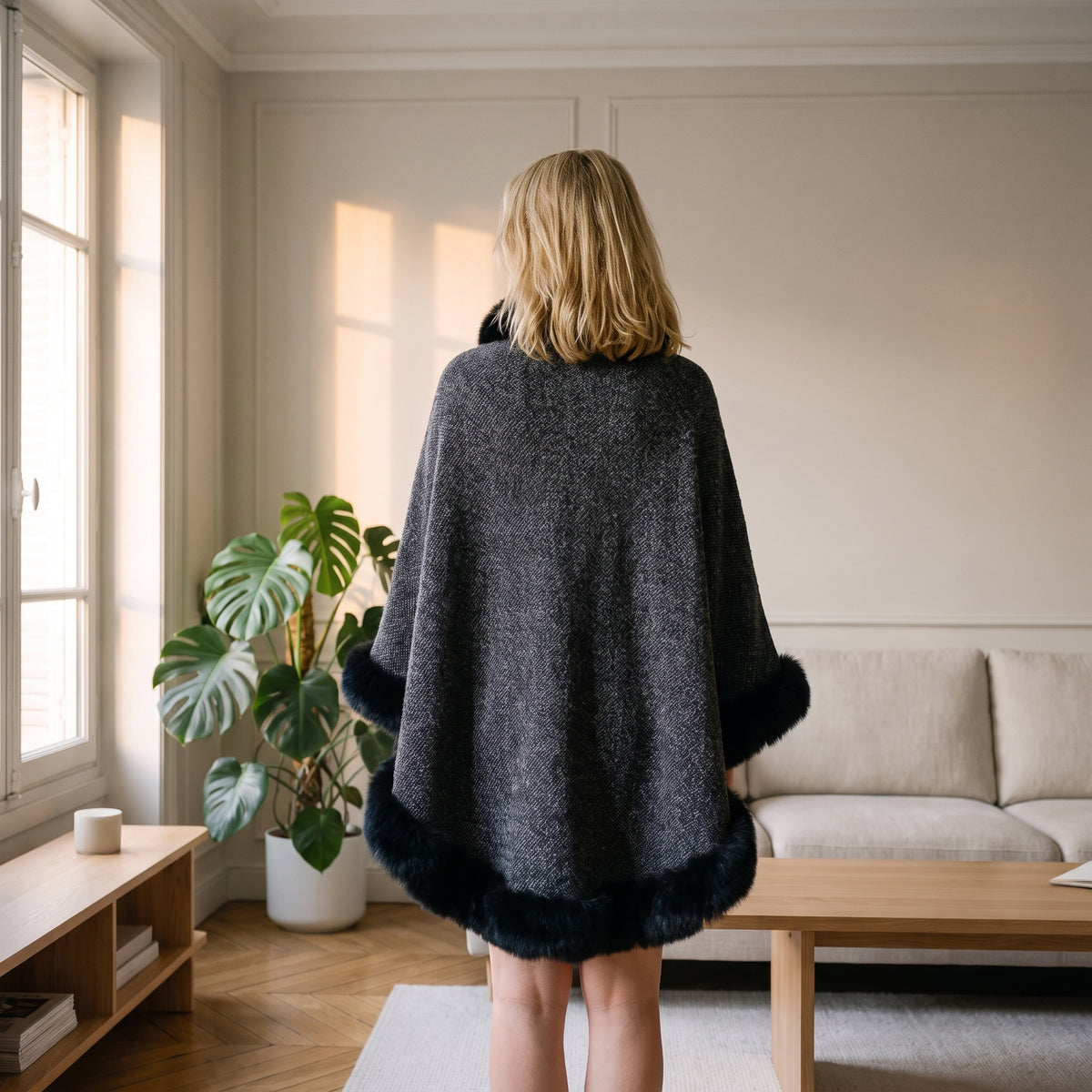 Vue de dos du poncho femme épais gris foncé porté près d'une fenêtre de salon Image