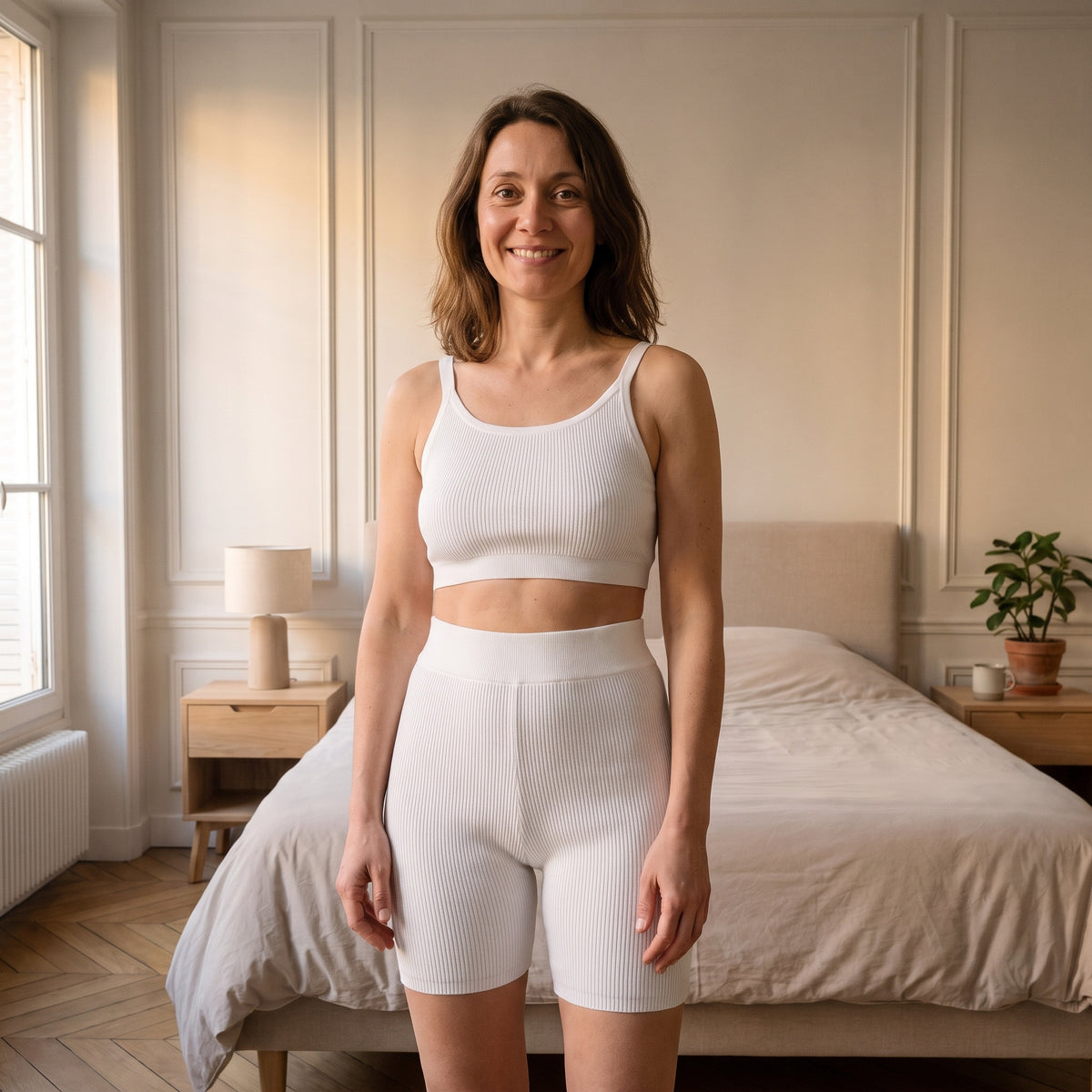 Femme portant l'ensemble d'intérieur en maille côtelée blanc, débardeur court et short taille haute, debout dans une chambre