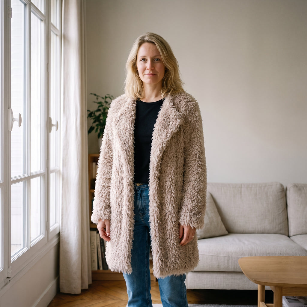 Femme du casting portant le manteau mi-long beige à poils dans un salon clair