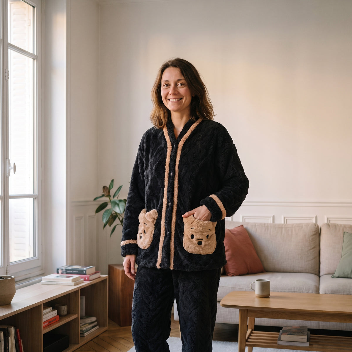 Femme en pyjama en peluche ourson noir, debout dans un salon