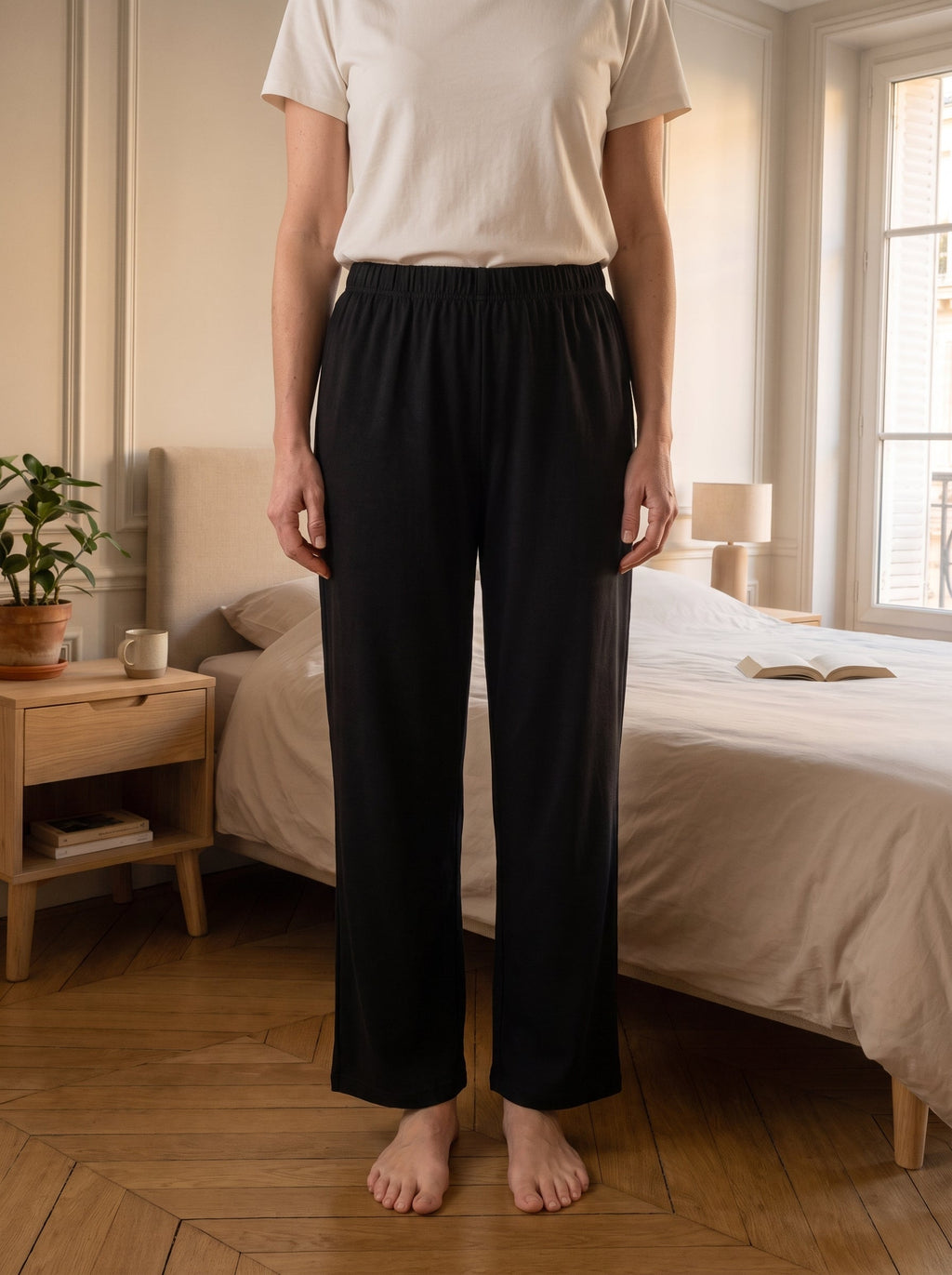 Bas de pyjama noir porte debout de face, les deux jambes tombent droites et paralleles jusqu au parquet.
