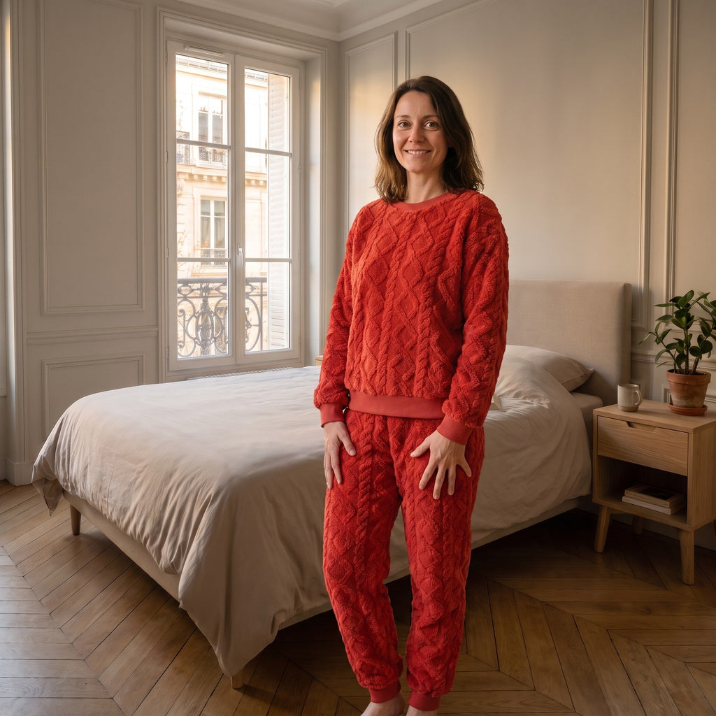 Femme portant l'ensemble pyjama rouge vif en coton effet tricot, debout dans sa chambre