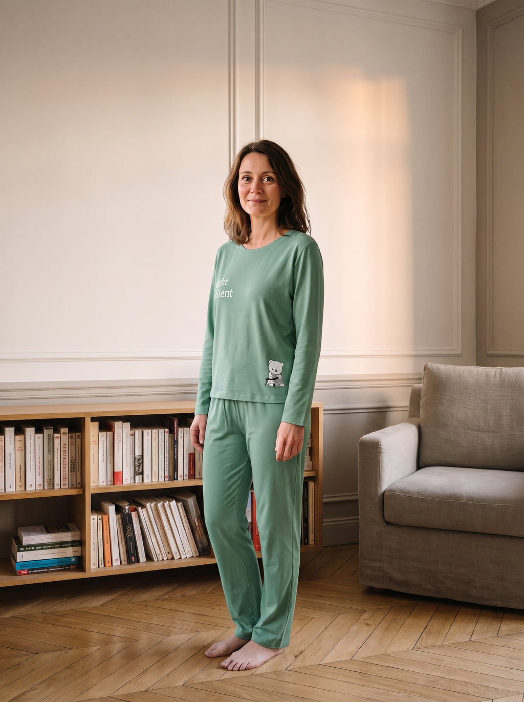 Ensemble pyjama vert d eau porte debout devant la bibliotheque, deux mots ecrits en blanc sur la poitrine.