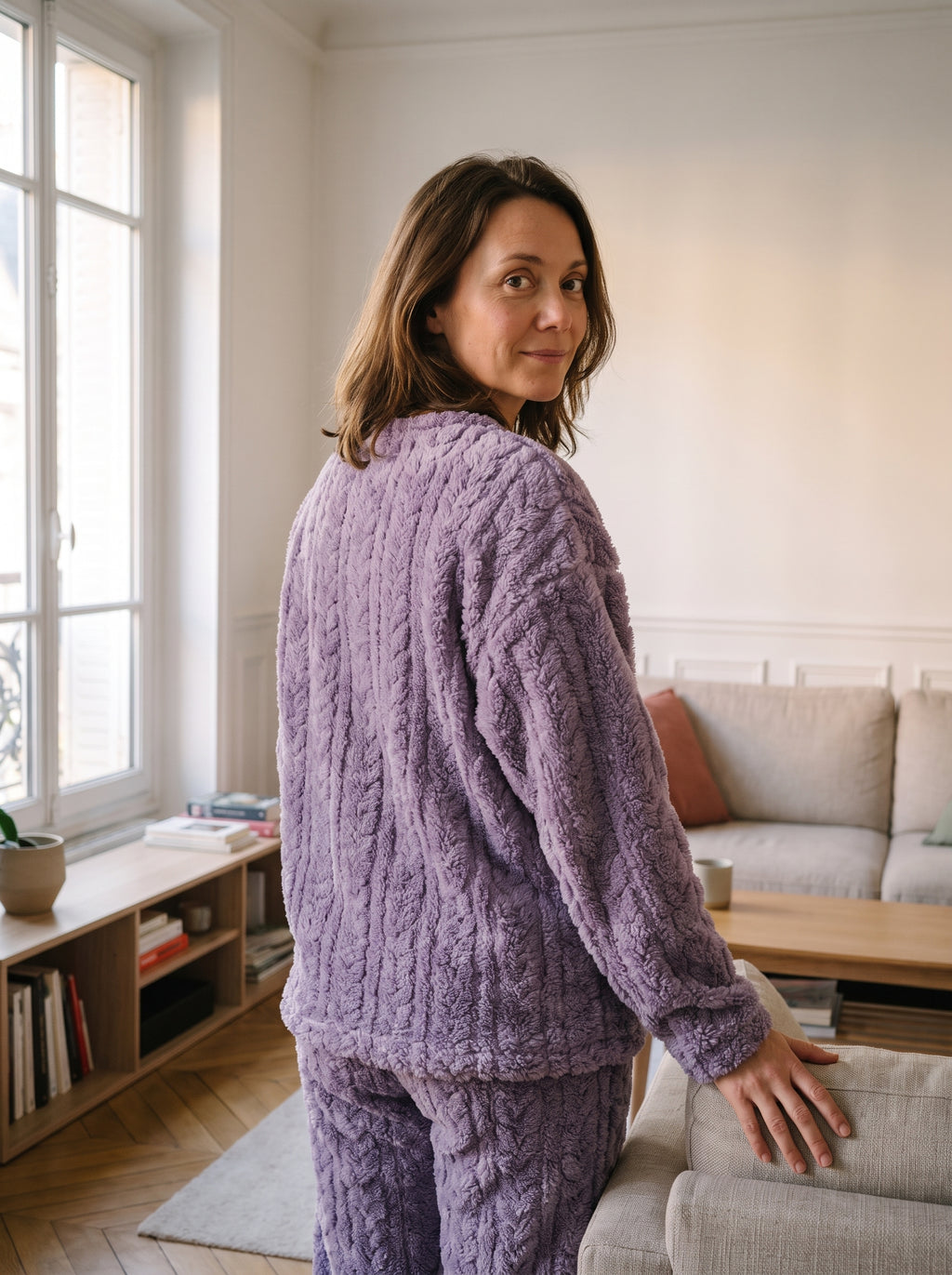 Pyjama femme en velours polaire violet a torsades, porte de trois quarts pres du canape