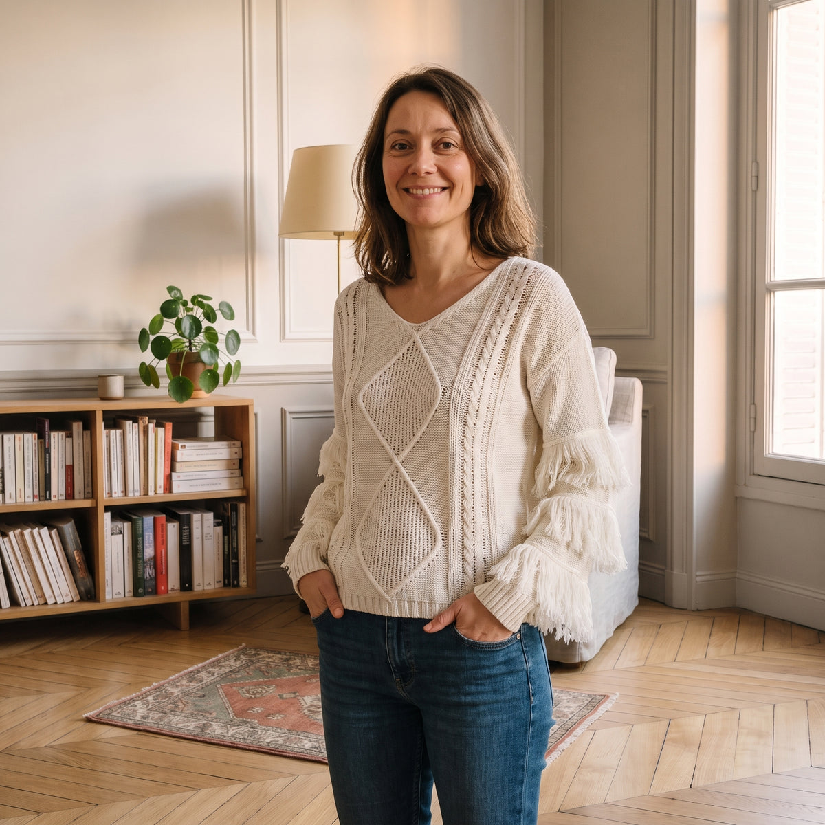 Pull écru à franges porté, mains dans les poches