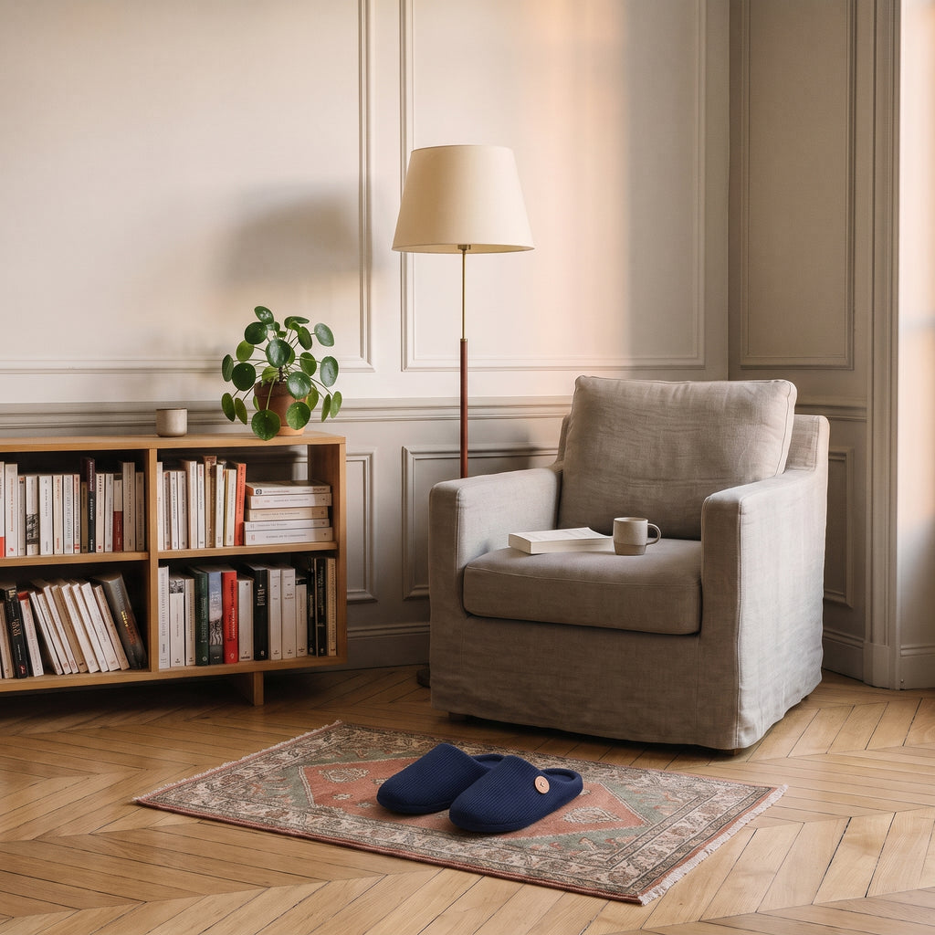Chaussons homme bleu marine posés au pied du fauteuil de lecture
