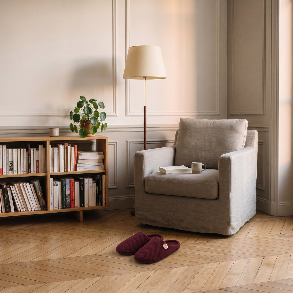 Chaussons homme bordeaux posés au pied du fauteuil de lecture
