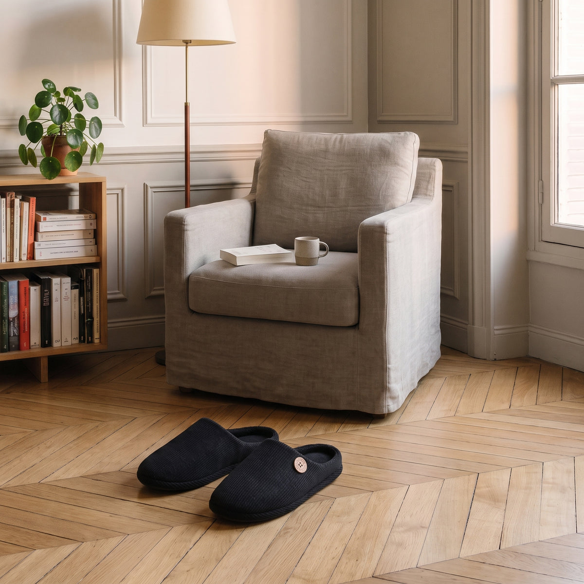 Chaussons homme noir posés au pied du fauteuil de lecture