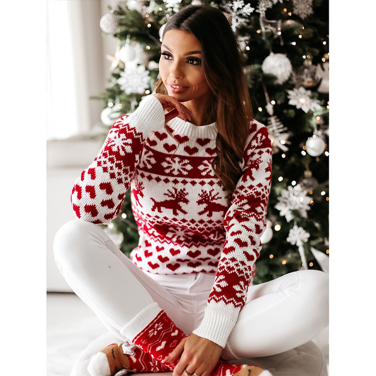Pull de Noël femme rouge et blanc porté dans un décor de fête Image