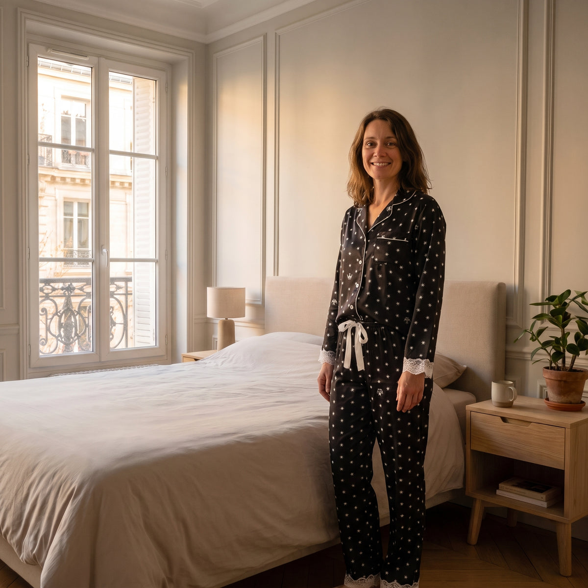 Pyjama en satin et dentelle noir porté par une femme debout Image