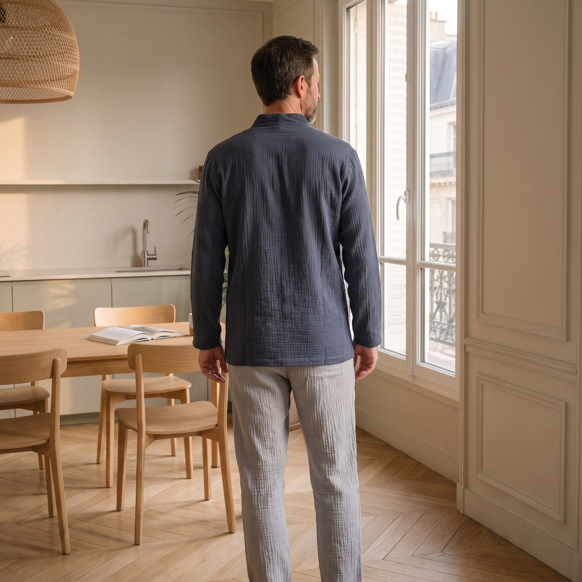 Homme de dos en pyjama de double gaze de coton devant la fenêtre du coin repas Image