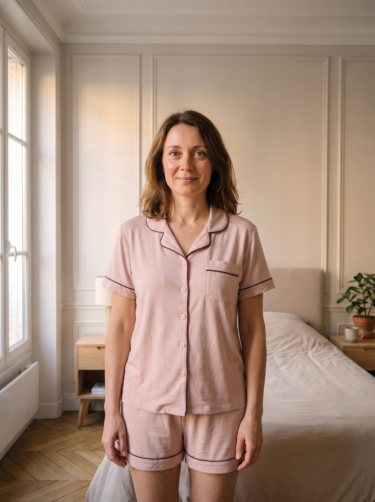 Femme du casting portant le pyjama d’été rose dans une chambre lumineuse.