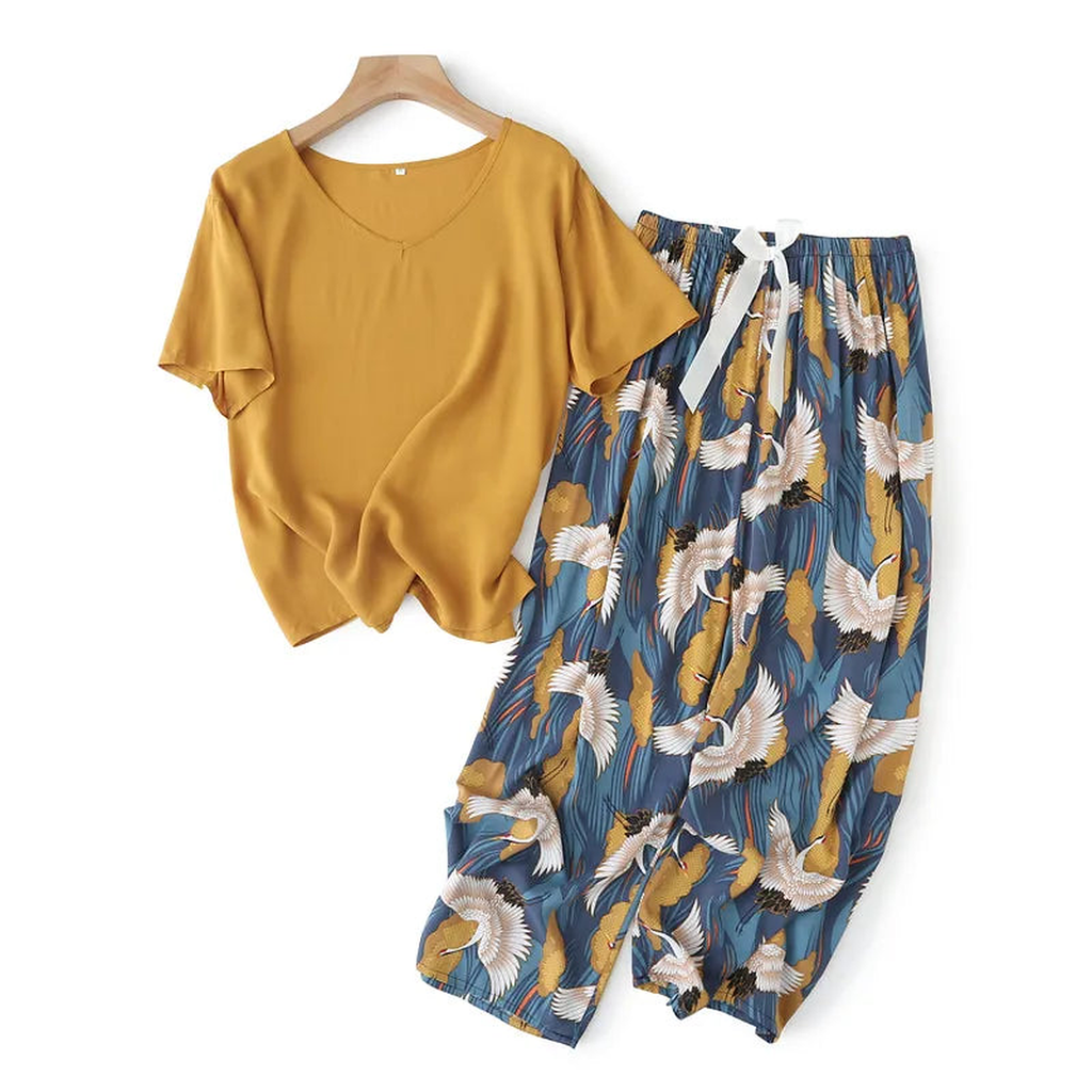 Pyjama deux pièces femme. Haut moutarde et pantalon large marine à grues, posés à plat sur un cintre.