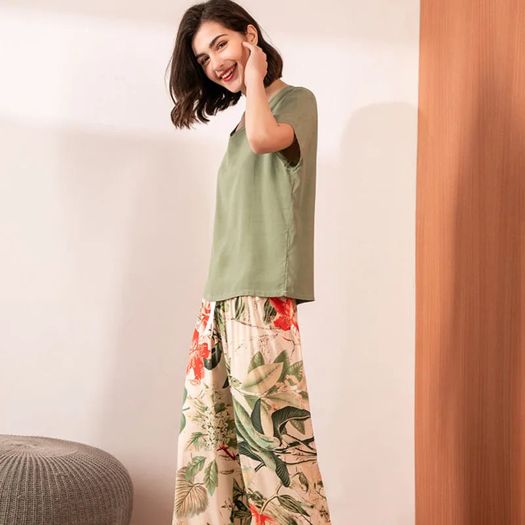 Pyjama deux pièces femme. Haut kaki et pantalon large beige à feuillages corail, portés debout, de trois quarts.