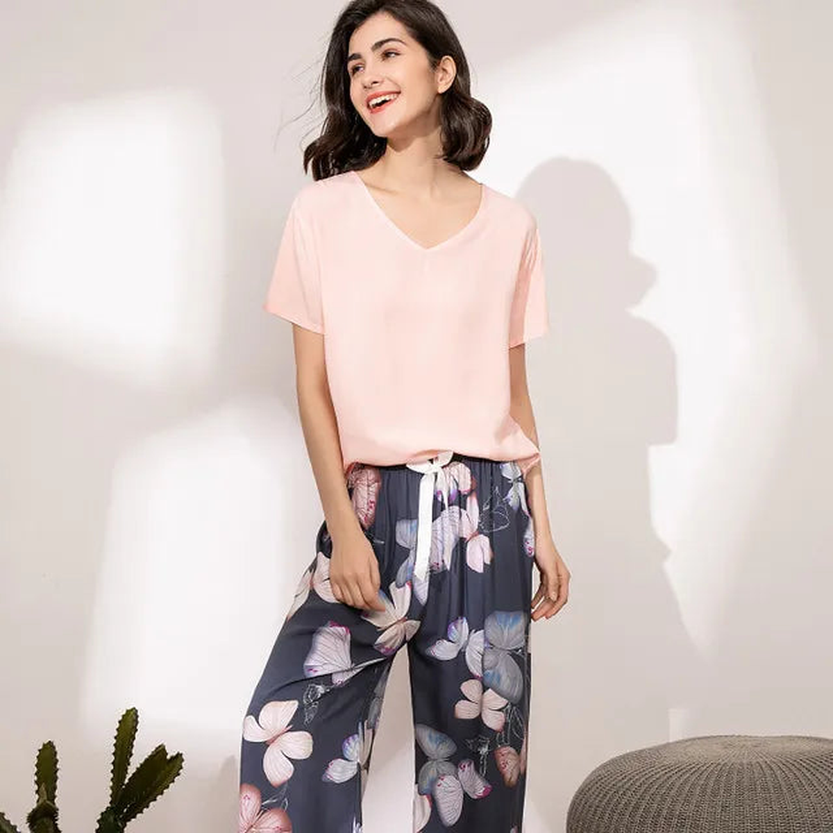 Pyjama femme, haut rose et pantalon large lys bleus marine, portés debout devant un mur clair.
