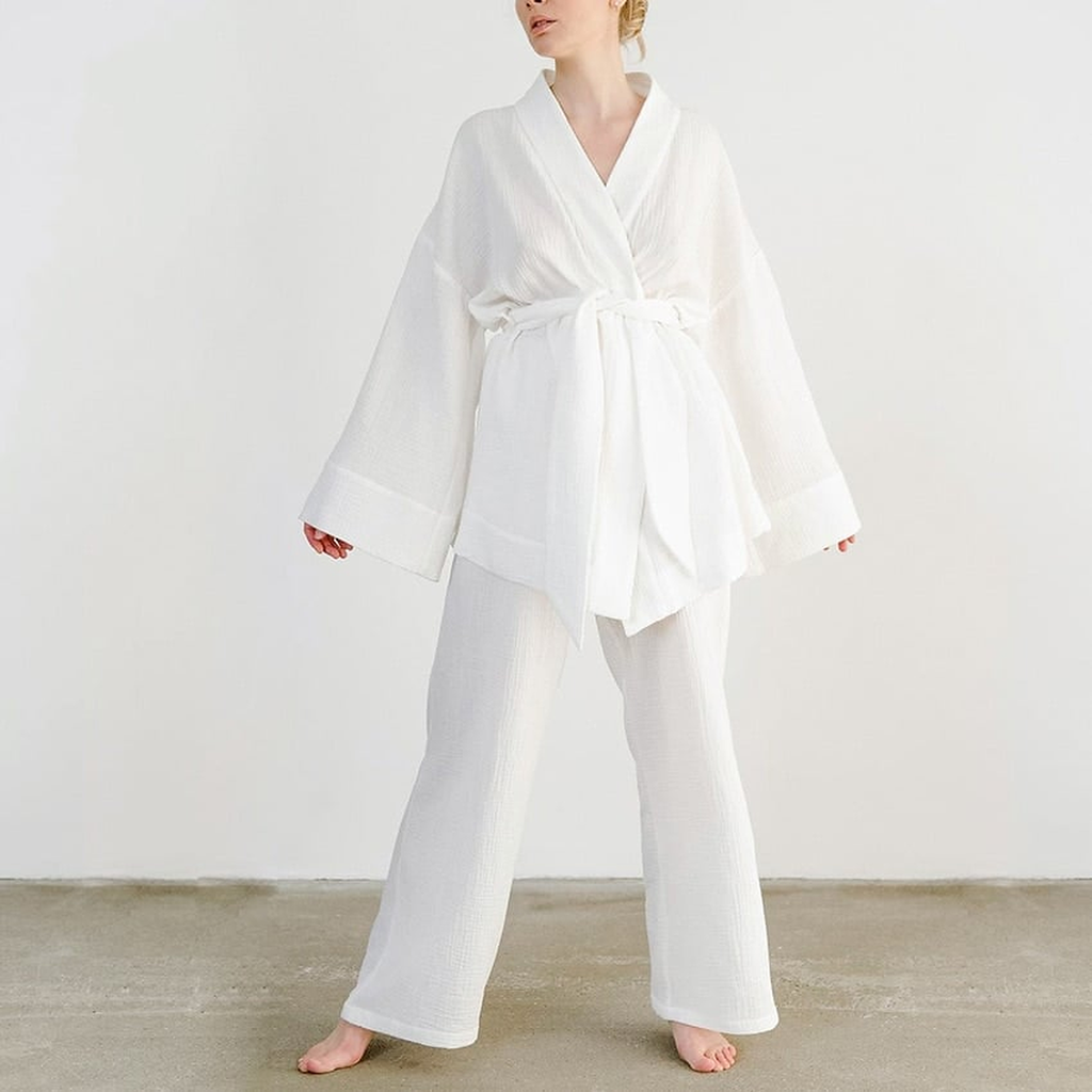 Pyjama kimono blanc porté pieds nus, la ceinture nouée en large nœud à la taille